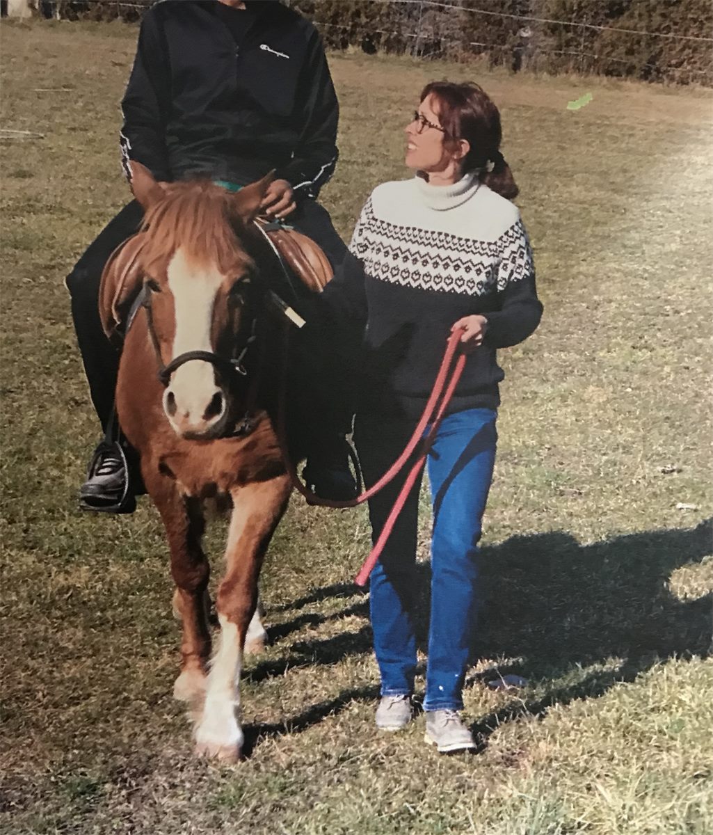 Sandra Theubet marche à côté d’un cheval monté, longe à la main